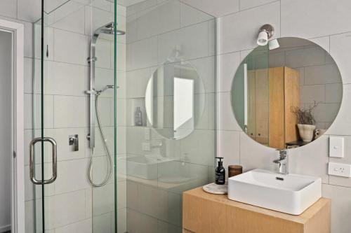 een badkamer met douche, wastafel en spiegel bij NEW - 2BR Beachfront unit at Okitu Beach! in Gisborne