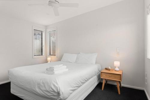 een witte slaapkamer met een wit bed en een tafel bij NEW - 2BR Beachfront unit at Okitu Beach! in Gisborne