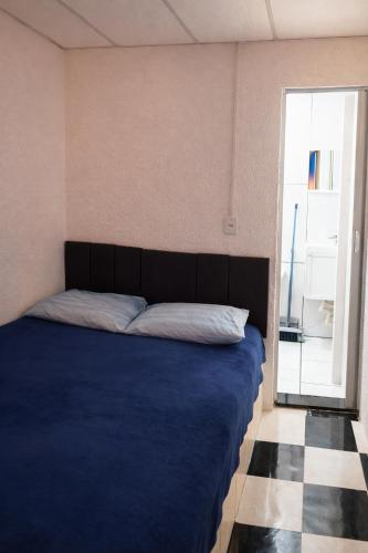 a bedroom with a bed with a blue blanket and a window at Peró Beach Hospedaria in Cabo Frio
