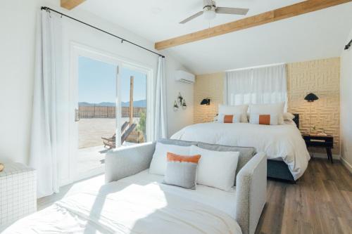 a bedroom with a bed and a couch and a window at Wanderlust- Desert Escape Stargazing Fire Pit in Twentynine Palms
