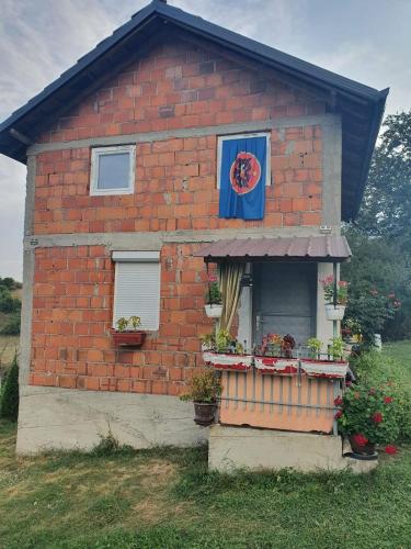 una casa di mattoni rossi con una finestra e dei fiori di Katun a Kosovska Mitrovica
