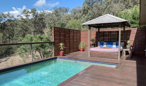 een bed en een prieel naast een zwembad bij Wild Edge Retreat in Wollombi