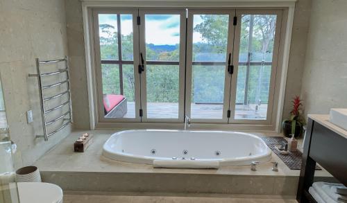 een grote badkamer met een bad en een groot raam bij Wild Edge Retreat in Wollombi