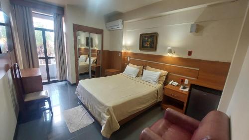 a hotel room with a bed and a chair at Hotel San Andres in Coronel Oviedo