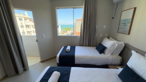 a hotel room with two beds and a window at Luísa Studio Hotel in Florianópolis