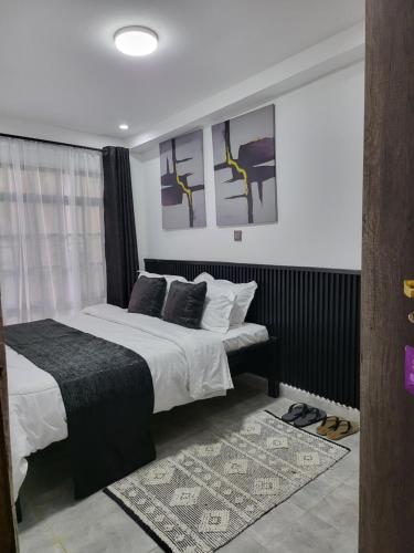 内罗毕The Akenza Cottage的一间卧室配有一张床,墙上挂着一些绘画作品