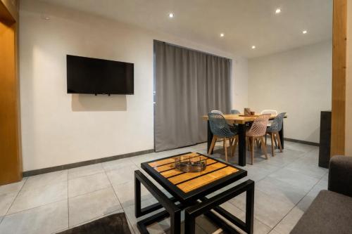 a living room with a table and a television on a wall at Gite Le ptit plus à Gérardmer in Gérardmer