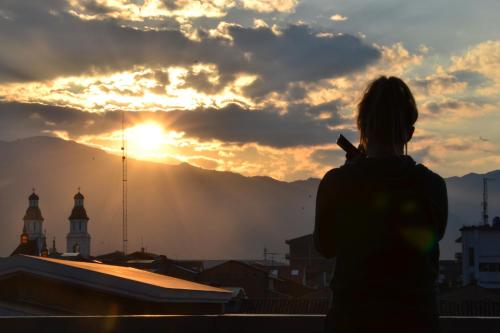 a woman standing on a roof looking at the sunset at El Cafecito Hostel Cuenca in Cuenca