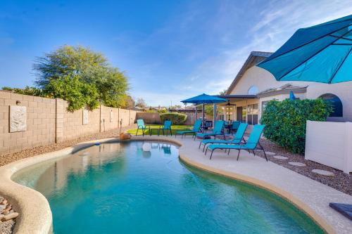 a swimming pool with chairs and umbrellas next to a house at Close to Spring Training! Outdoor Oasis in Gilbert in Gilbert