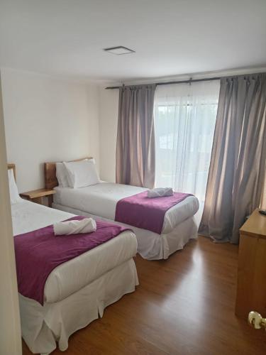 two beds in a room with a window at Hostal Doble E Patagonia in Puerto Natales