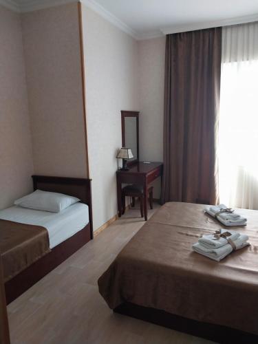 een hotelkamer met twee bedden en een bureau bij Guest house Keria in Tsʼageri