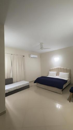 a white room with two beds and a window at Tribal Lodge in Karachi