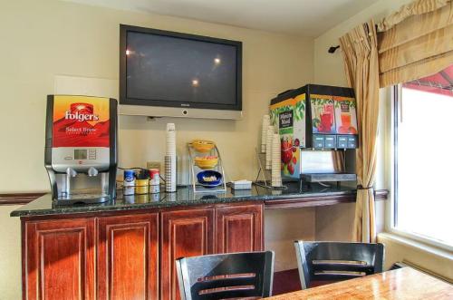 a bar with a television on a wall with chairs at Days Inn by Wyndham Market Center Dallas Love Field in Dallas