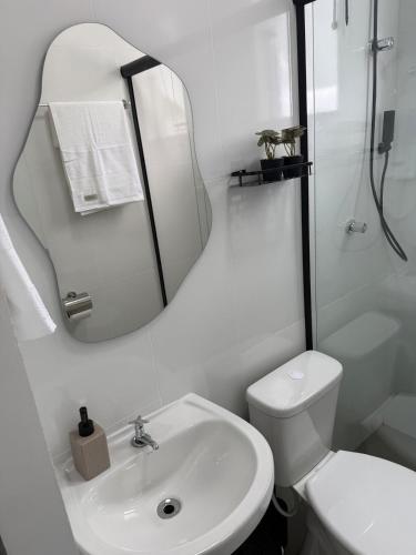 ein weißes Badezimmer mit Waschbecken und Spiegel in der Unterkunft Studio 218, Lavras, Minas Gerais in Lavras