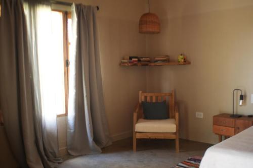 een slaapkamer met een bed, een stoel en een raam bij La Paz suites de campo in Capilla del Señor