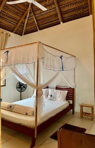 ein Schlafzimmer mit zwei Betten mit Himmelbett in der Unterkunft Kategha Beach Guesthouse in Praia do Tofo