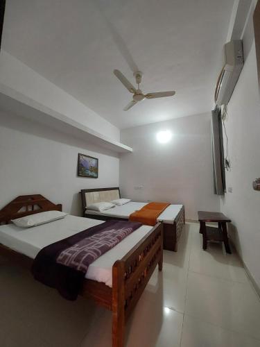 a bedroom with two beds and a ceiling fan at SOU Mahadev Homestay in Garudeshwar