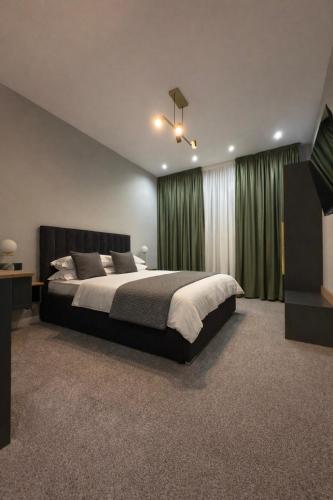 a bedroom with a large bed with green curtains at Elmax Aparthotel in Craiova