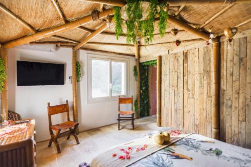 Gîtes Mas des rochers - Case bambou avec Spa في لو بوزيت: غرفة نوم بجدران خشبية وسرير وتلفزيون