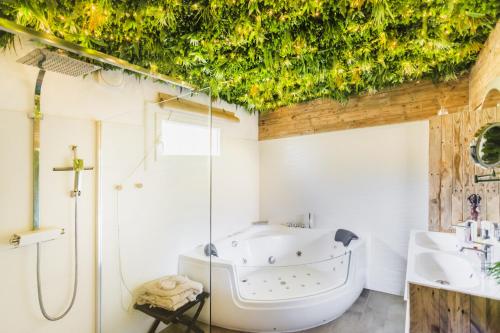 Gîtes Mas des rochers - Case bambou avec Spa في لو بوزيت: حمام مع حوض استحمام ودش ومغسلة