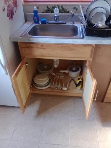 een gootsteen met borden en bestek eronder bij 1 BEDROOM KITCHEn BATHROOM ApT in Titusville