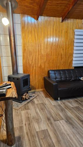a living room with a couch and a stove at Cabañas El Maiten de Castro in La Chacra