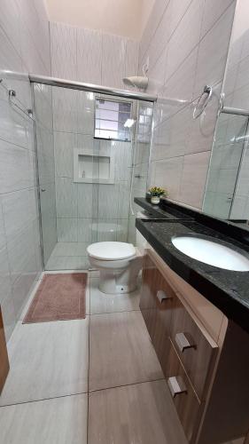 a bathroom with a toilet and a shower and a sink at Casa Requinte in Cascavel
