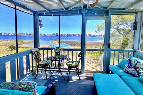 eine abgeschirmte Veranda mit einem Sofa, Stühlen und einem Tisch in der Unterkunft Island SunRise in Plum Island