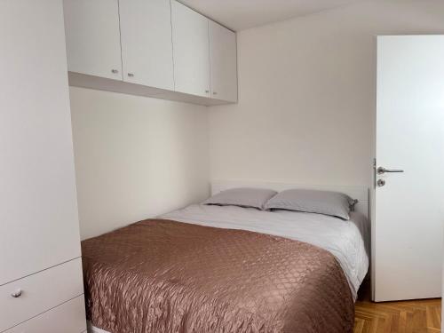 een kleine slaapkamer met een bed en witte kasten bij Odmori se, Centar apartman in Donje Mladice