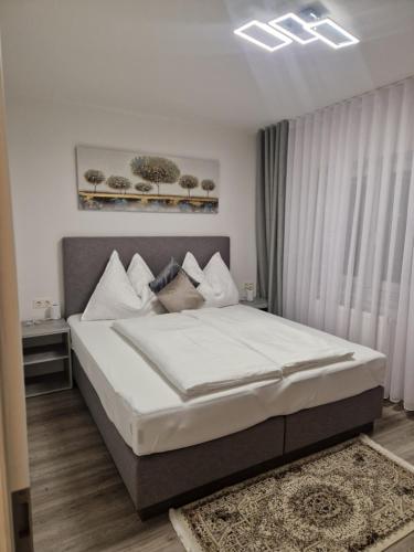een slaapkamer met een groot bed met witte lakens en kussens bij Appartement Sami in Altenmarkt im Pongau