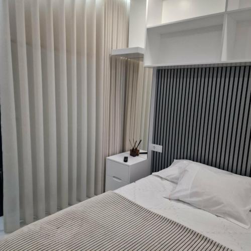 a bedroom with a white bed and a black and white curtain at Quintinha dos Queiroses in Vila Boa de Quires