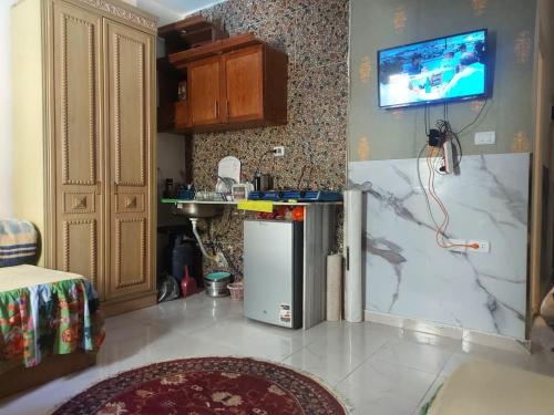een keuken met een koelkast en een tv aan de muur bij Luxury Studio in Hurghada