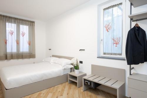 een witte slaapkamer met een bed en twee ramen bij Prince Residence in Castellammare di Stabia