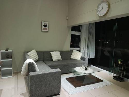 a living room with a couch and a clock on the wall at African Nest in Windhoek