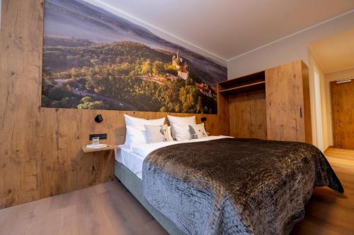 een slaapkamer met een groot bed met een schilderij aan de muur bij Waldhotel Hohe Sonne in Eisenach
