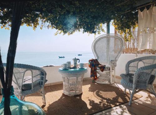 een patio met stoelen en een tafel met uitzicht op de oceaan bij The Artist's Farm in Dhiyeliótika