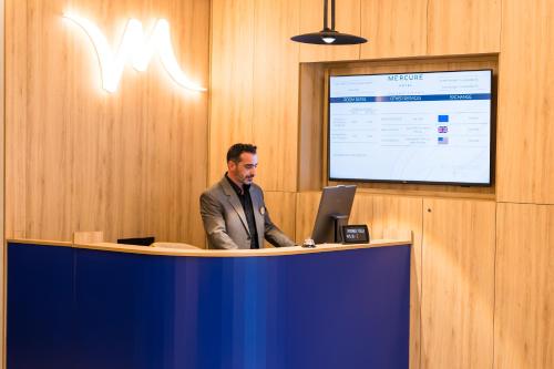 een man aan een bureau met een laptop bij Mercure Bucharest Cantemir in Boekarest