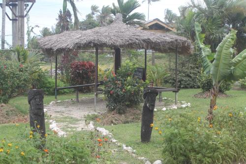 a small hut with a grass roof in a garden at Shalini Garden Hotel & Apartments in Singatoka