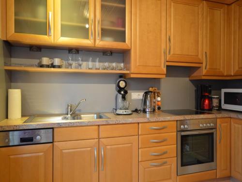 a kitchen with wooden cabinets and a sink at Wunderschöne Ferienwohnung im Burgenland in Manderscheid