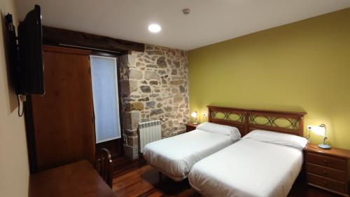 1 Schlafzimmer mit 2 Betten und einer Steinmauer in der Unterkunft Ostatu de zegama in Zegama
