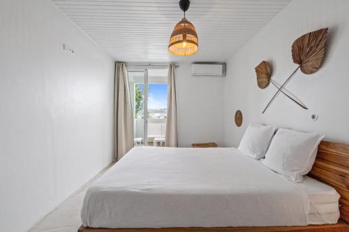 a bedroom with a large white bed and a window at Casa Blanca in La Trinité