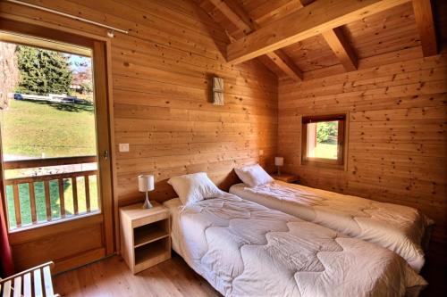 twee bedden in een blokhut met een raam bij Chalets à Saint Jean d'Aulps - Coffy MAE-3601 in Saint-Jean-dʼAulps