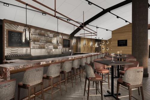 a restaurant with a bar with chairs and tables at Grand Hyatt DFW Airport in Irving