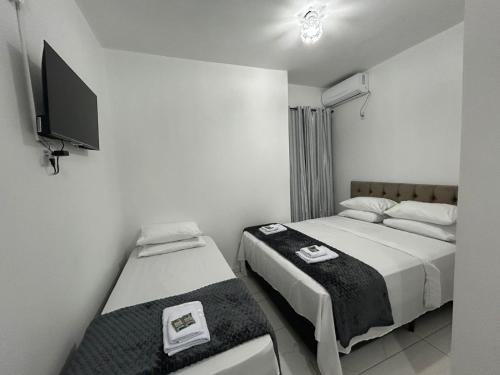 a bedroom with two beds and a flat screen tv at HOTEL e POUSADA KF in Irapuá