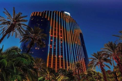 a tall building with palm trees in front of it at Masquerade Tower at Rio Hotel & Casino by Suiteness in Las Vegas