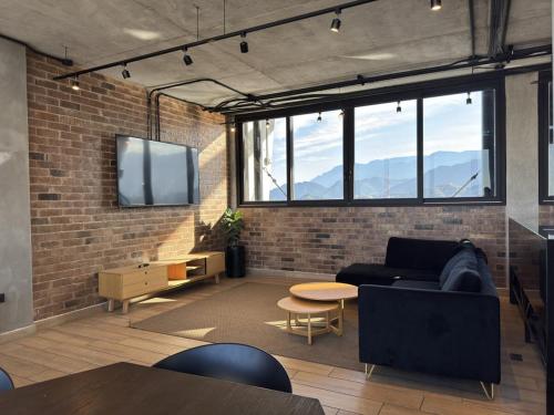 a living room with a couch and a tv on a brick wall at Loft Céntrico con Piscina, Gym y Vistas in Monterrey