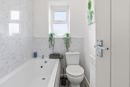 a white bathroom with a toilet and a bath tub at Modern 5 Bed 2 Bath House w Free Parking in Bury