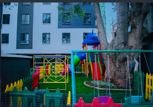 une aire de jeux devant un grand arbre dans l'établissement Sunny Charm Studio Wi-fi & Netflix, à Nairobi