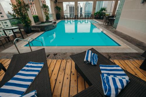 a large swimming pool with blue and white striped pillows at City Garden Hotel Makati in Manila