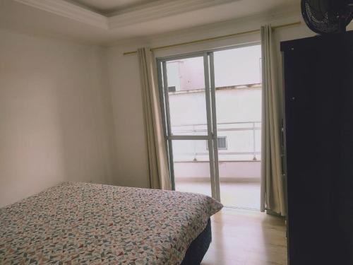 een slaapkamer met een bed en een groot raam bij Apartamento 150m das Termas in Piratuba